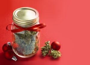 Festive Cannabis concept for Christmas holidays. Red background with red balls.