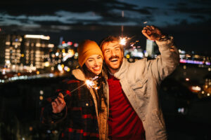 Romantic couple enjoying night view and sparklers on a rooftop party.