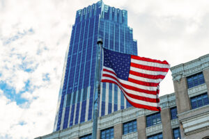 Veterans Day in America. City with flag. American Flag Waving in sky. 4th of July with American flag. Independence Day. National patriotic symbol. USA American flag. Memorial Day.
