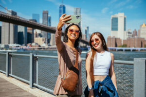 Asian friends enjoying sunny day in New York City with Manhattan skyline in the background
